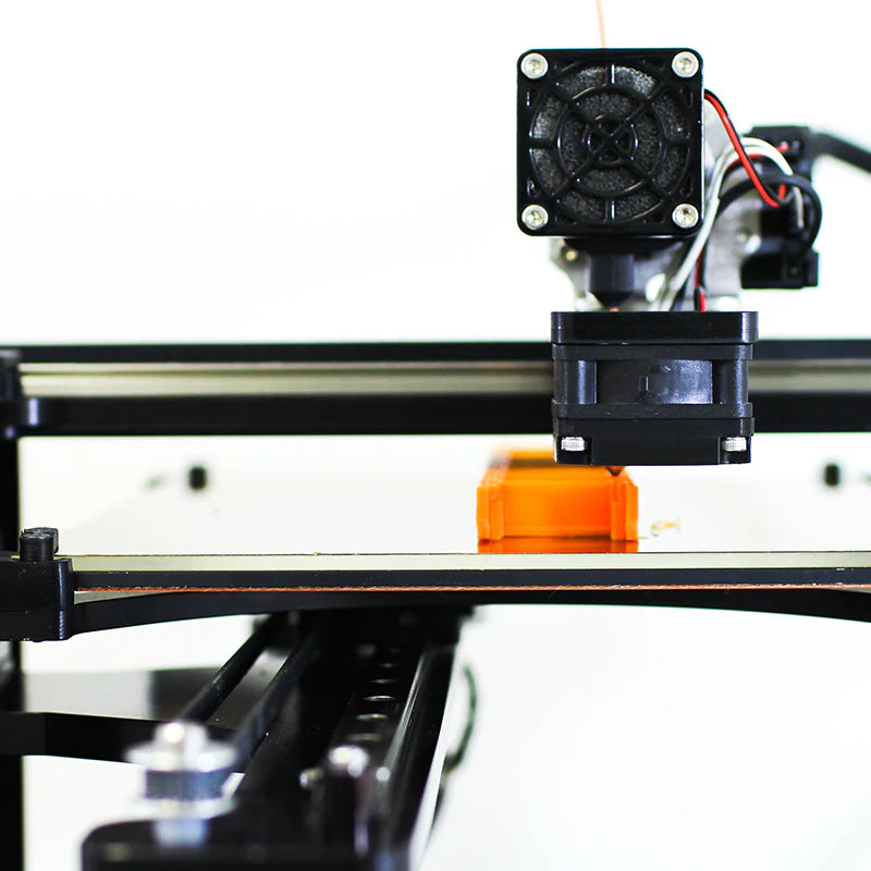 3D printer in operation with a close-up of the print head and bed.
