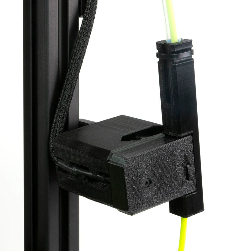 Black plastic filament feeder with filament running through it on a white background